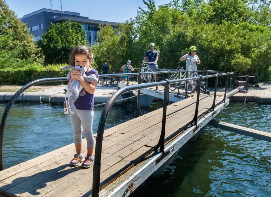 Child and participants are crossing Hartwells lock with their bikes at rideau Canal during their Ottawa tour with Escape