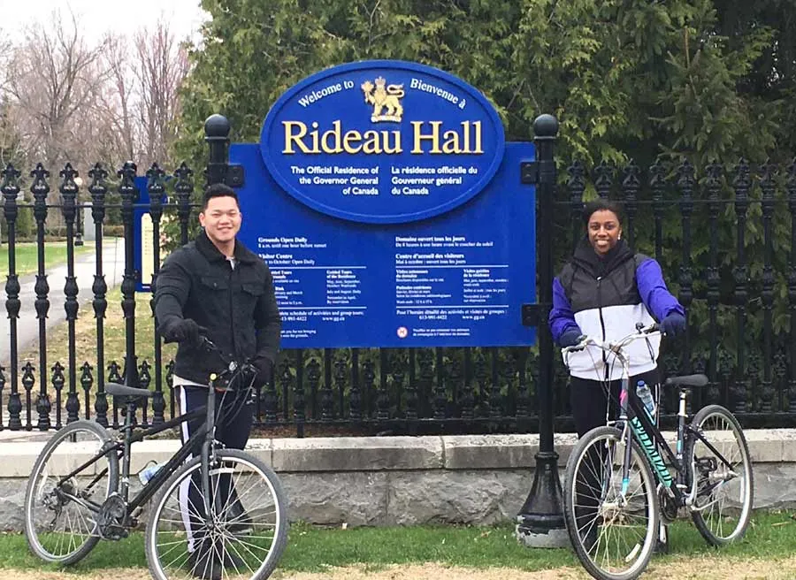Tour guide is taking a picture of a couple in front of Rideau Hall during Ottawa express guided bike tour with Escape