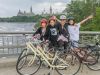 Family is biking on Ottawa river pathway with parliament building view during their Express tour by bike in Ottawa