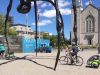 Parents biking with kids sitting on Escape rental child trailers, visiting Ottawa landmark, Maman spider sculpture 